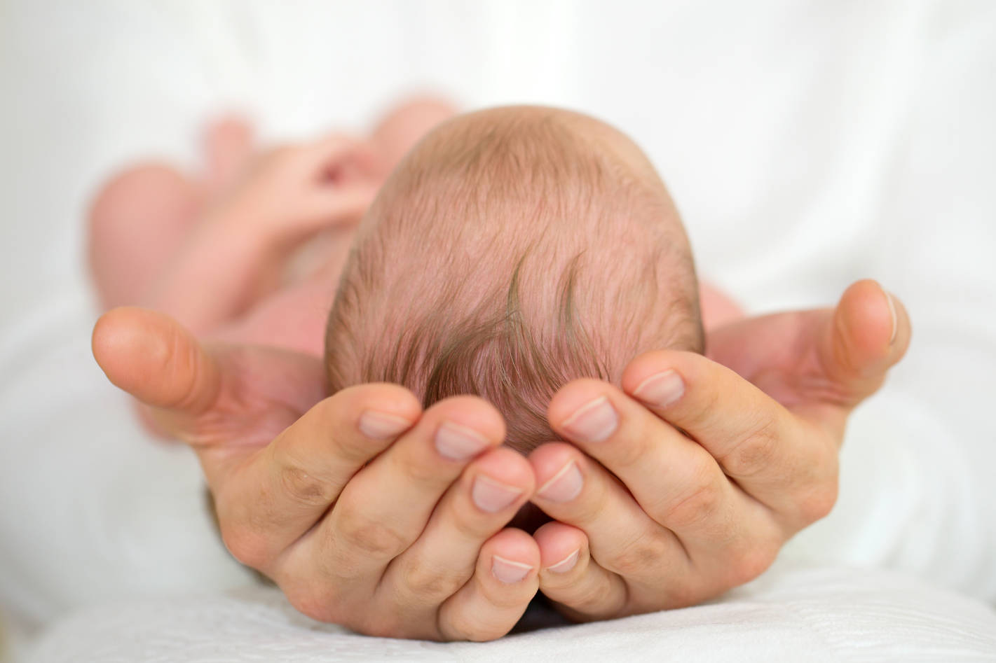 Men’s Hands holding newborn baby.